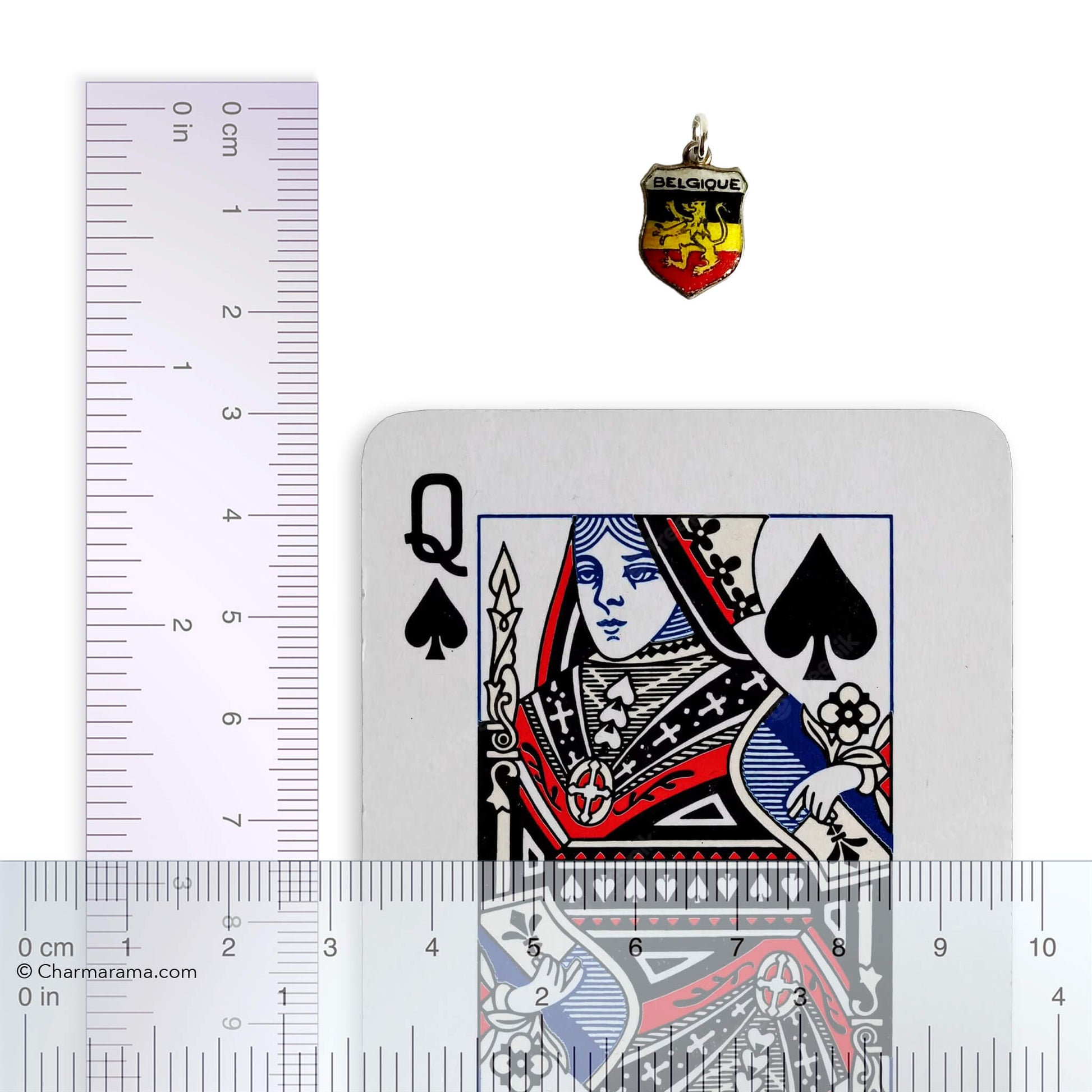 Vintage Belgium travel shield charm with playing card and ruler for scale on white background.