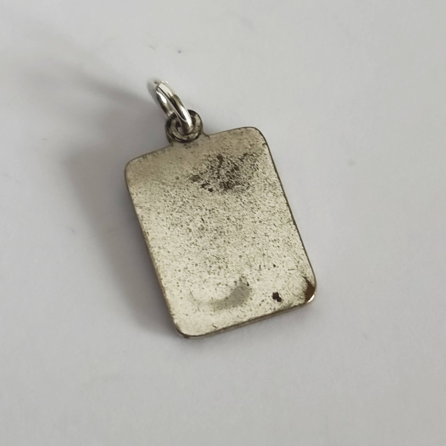Silver rectangular pendant on a light gray background