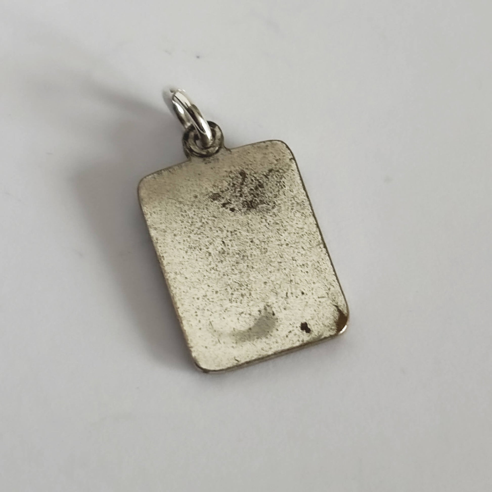 Silver rectangular pendant on a light gray background