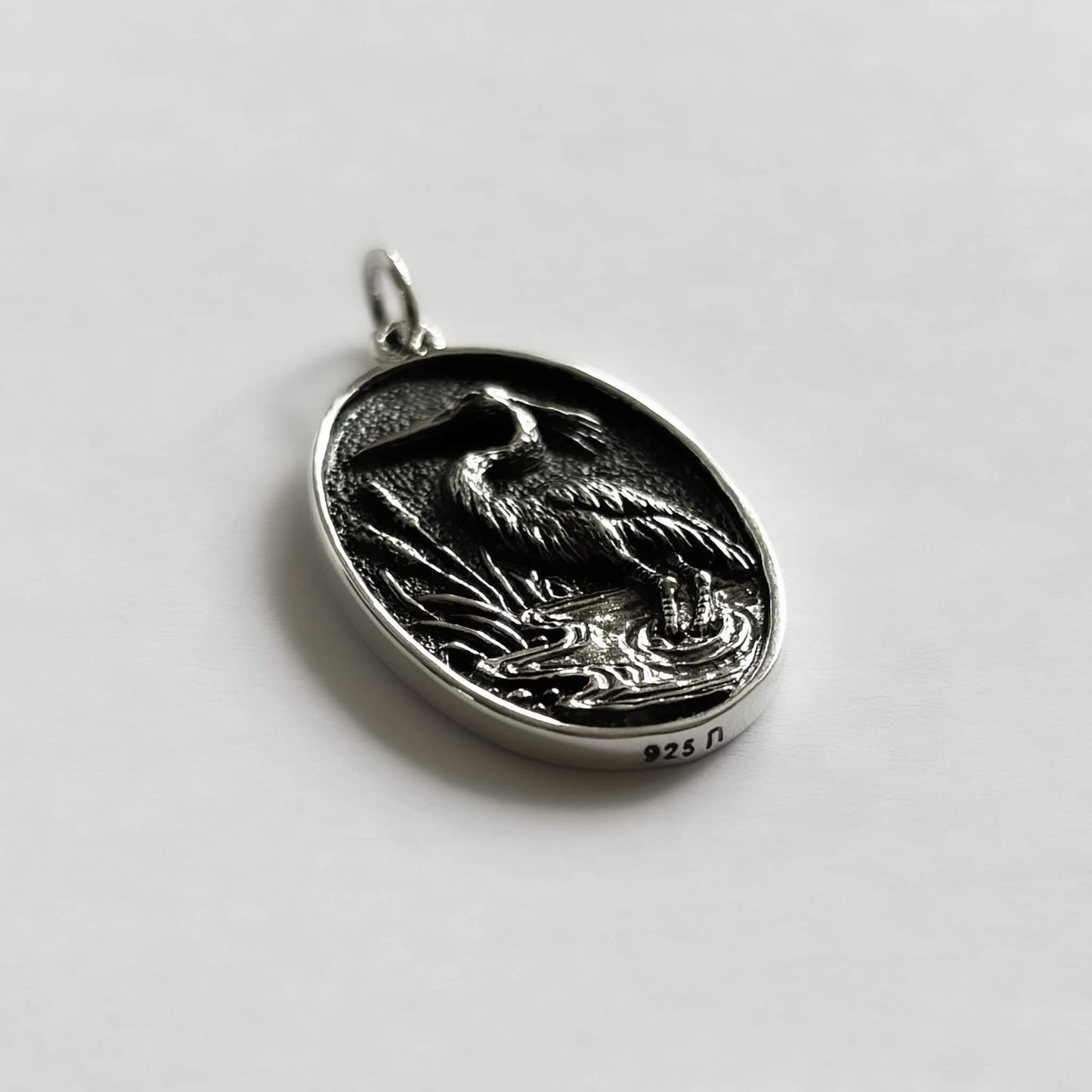 Side view of sterling silver heron in oval frame charm bird pendant from Charmarama