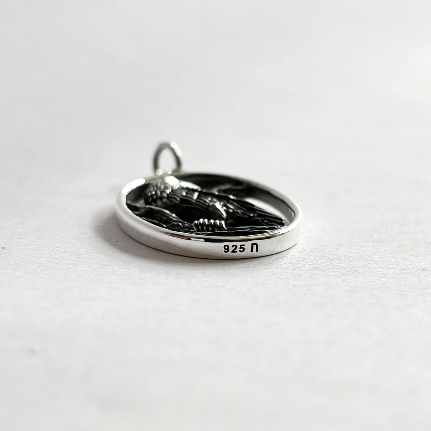 Crow in oval frame charm sterling silver bird pendant side view