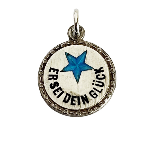 Silver pendant with blue star and German text on a white background
