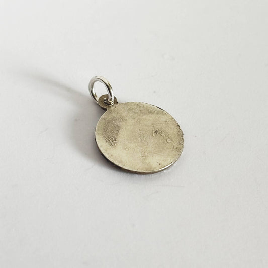 Round silver pendant on a light gray background