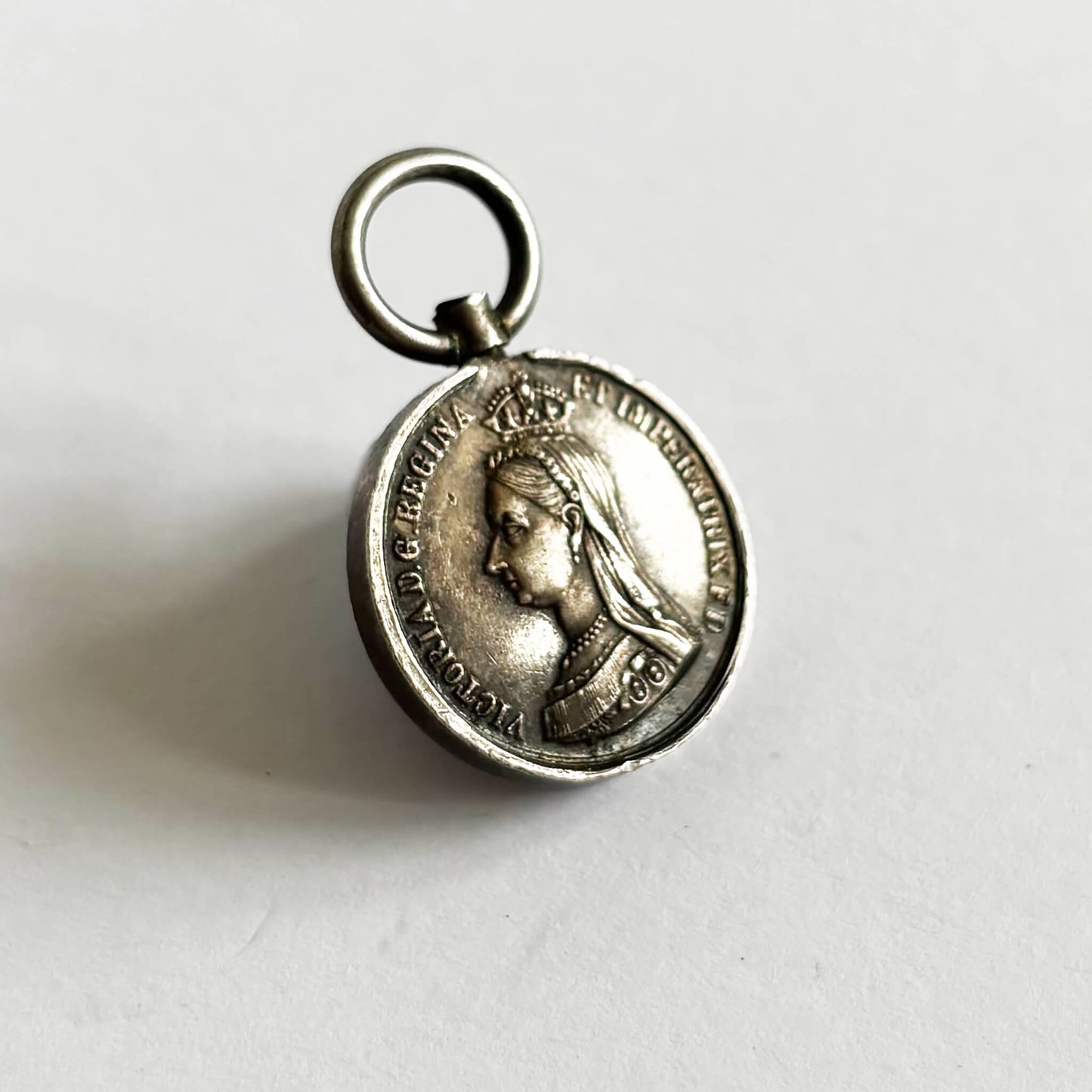 Silver pendant with Queen Victoria portrait on a white background