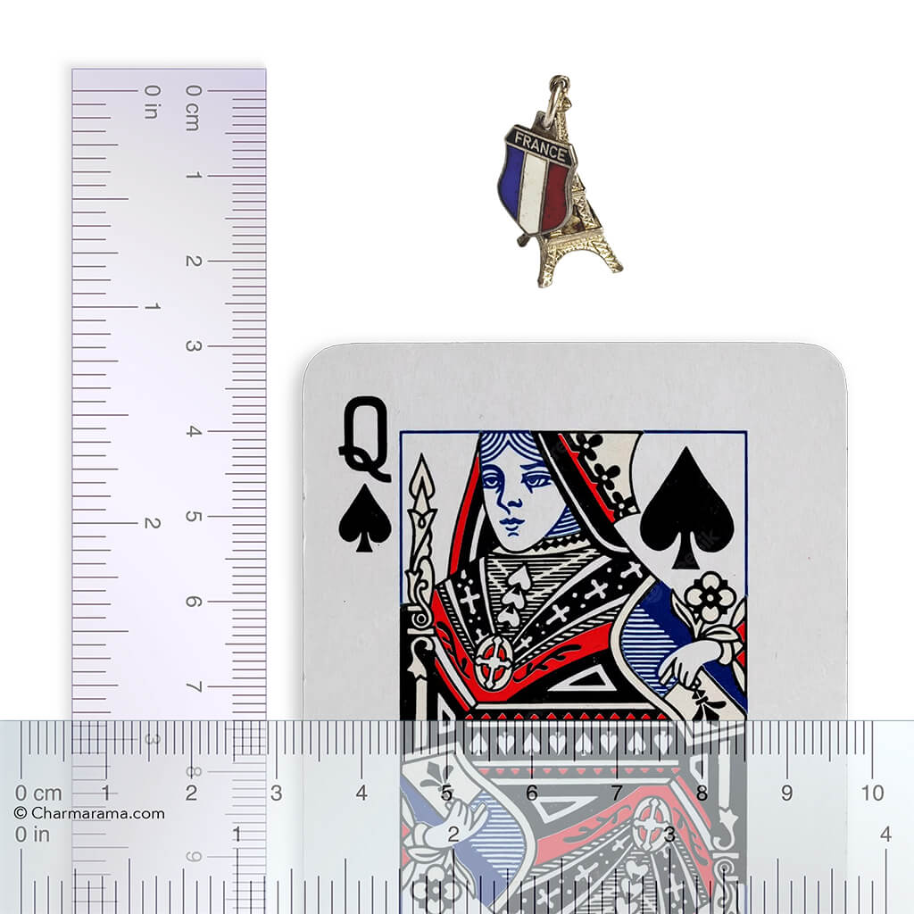 Playing card, Eiffel Tower charm, and ruler for scale on a white background
