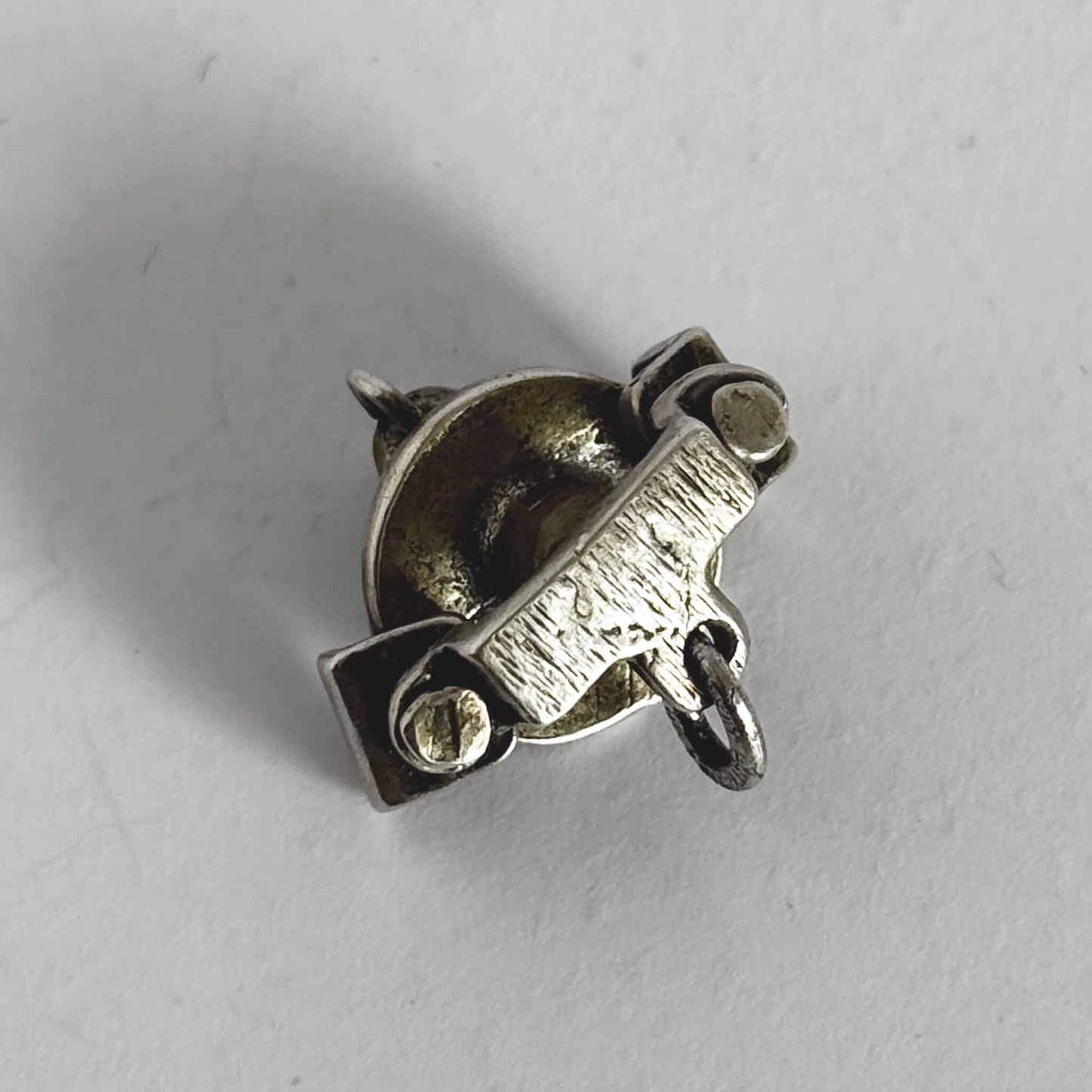 silver cafe table with teacups and teapot charm viewed from beneath on a grey background