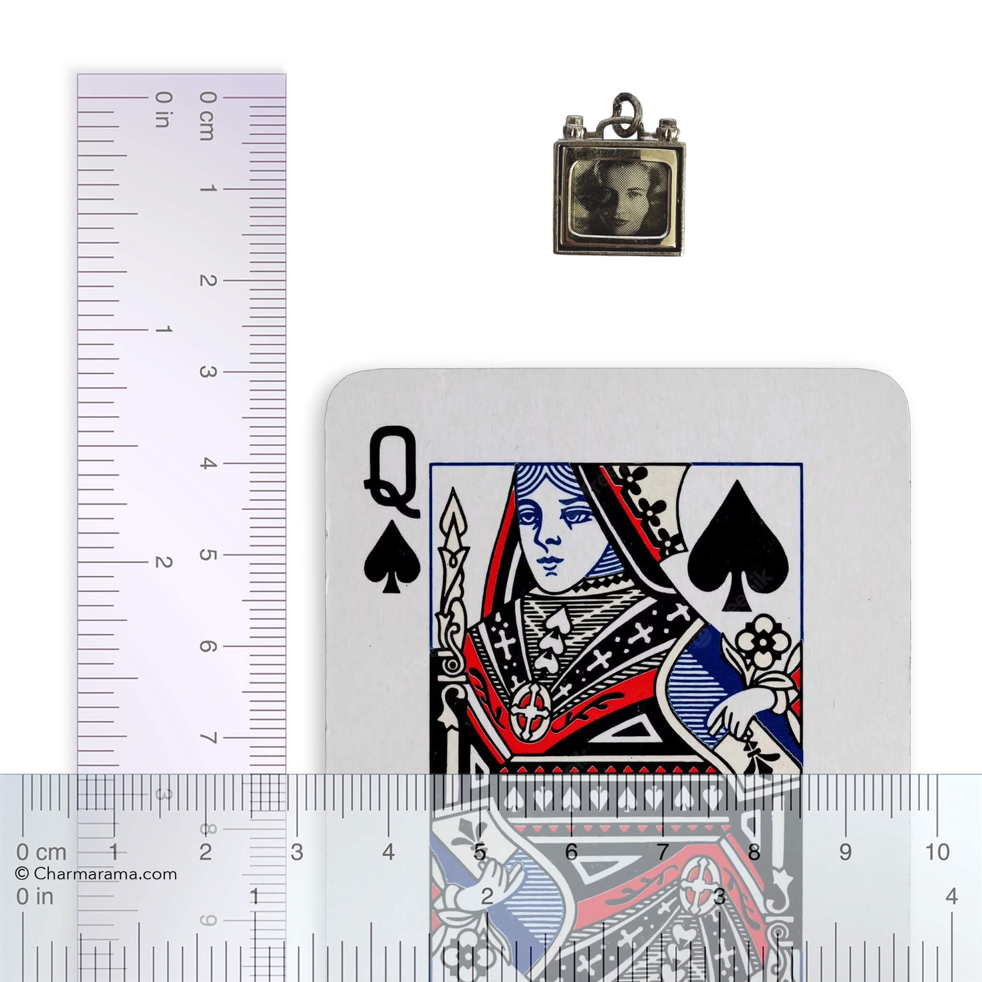 Vintage silver television charm with laying card and ruler for scale on a white background