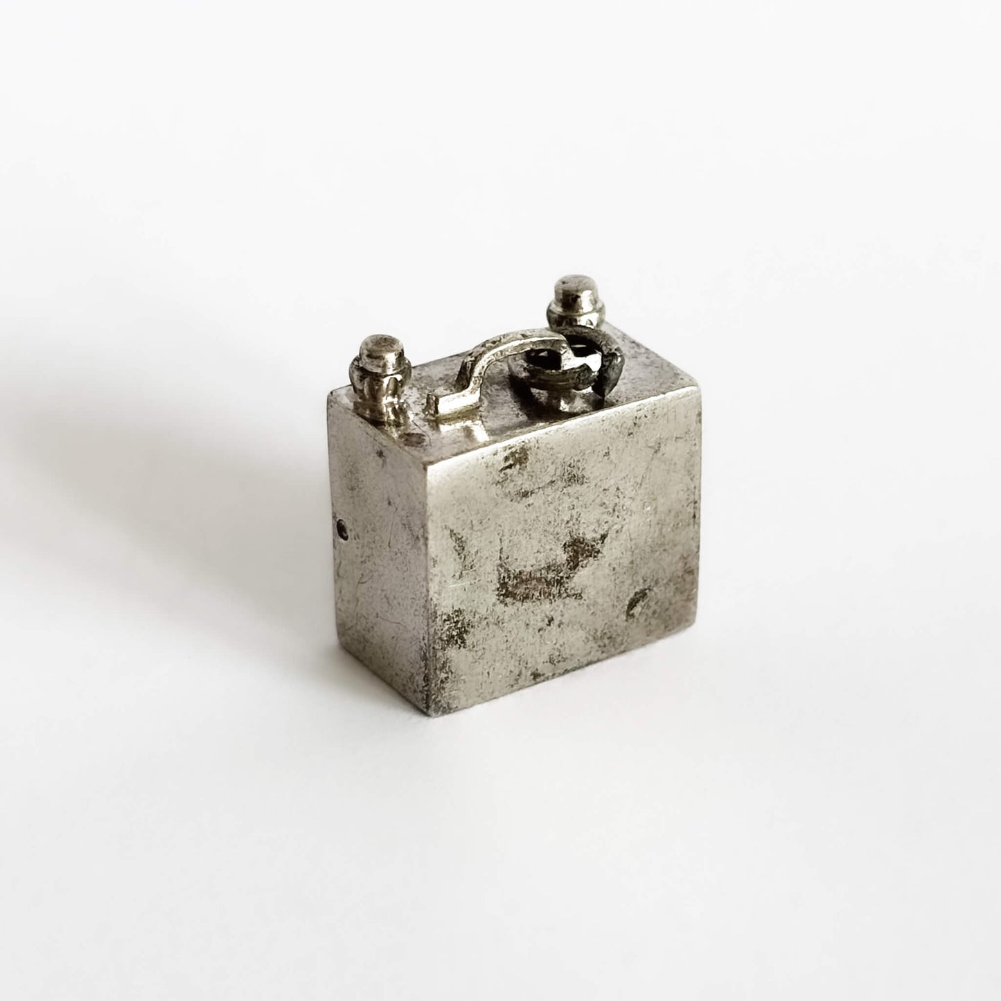 Vintage silver television charm viewed from back on a white background
