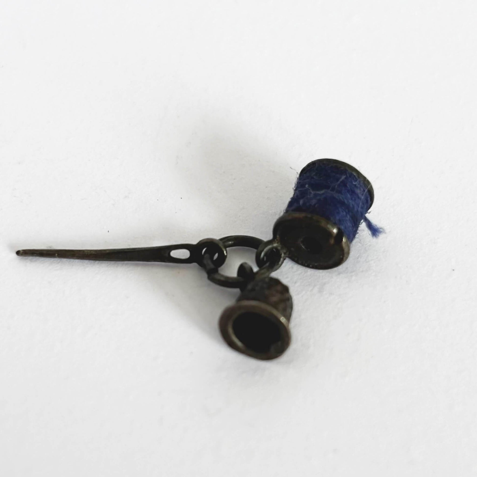Sterling silver thimble needle and cotton reel charm on a white background