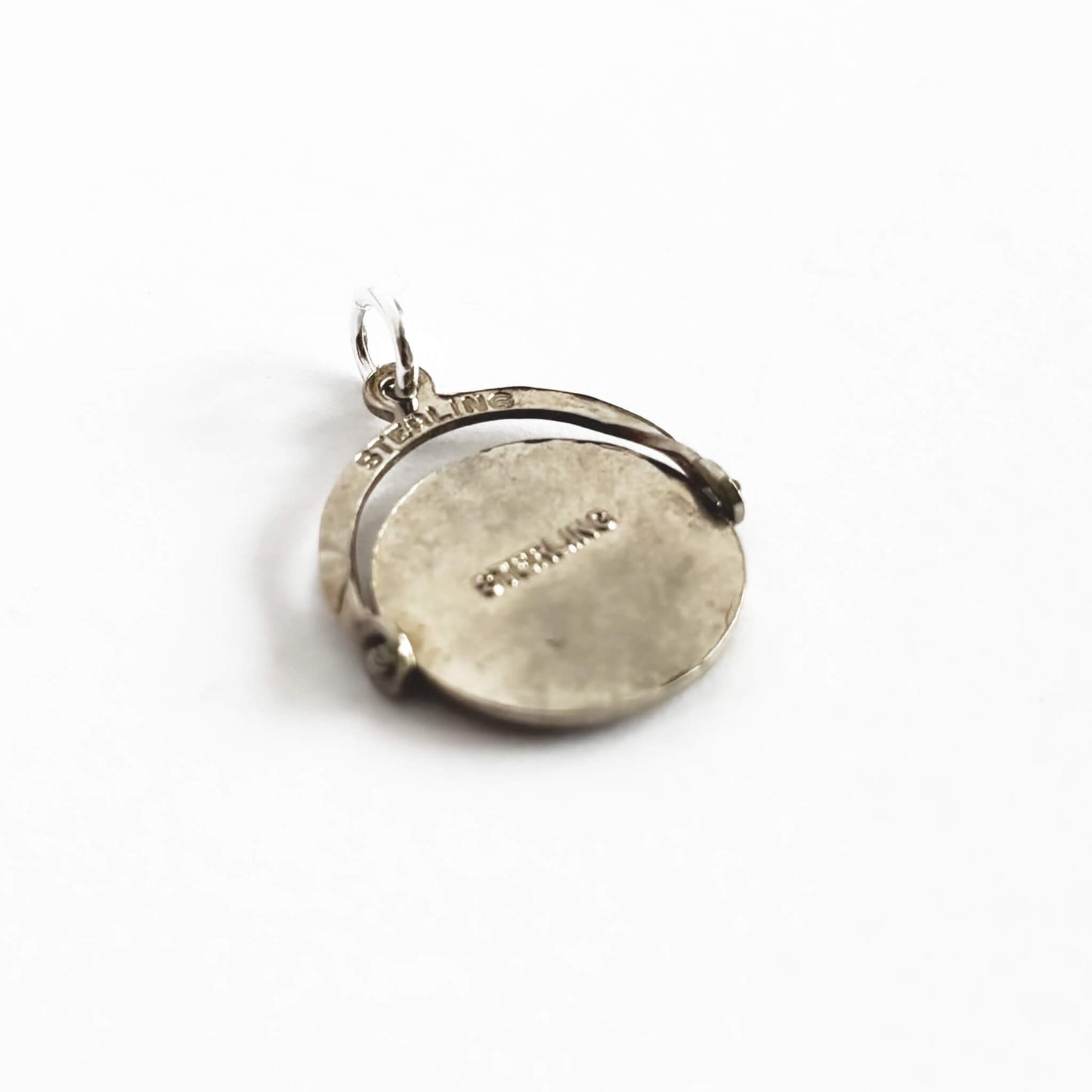 Silver pendant with engraved text on a white background