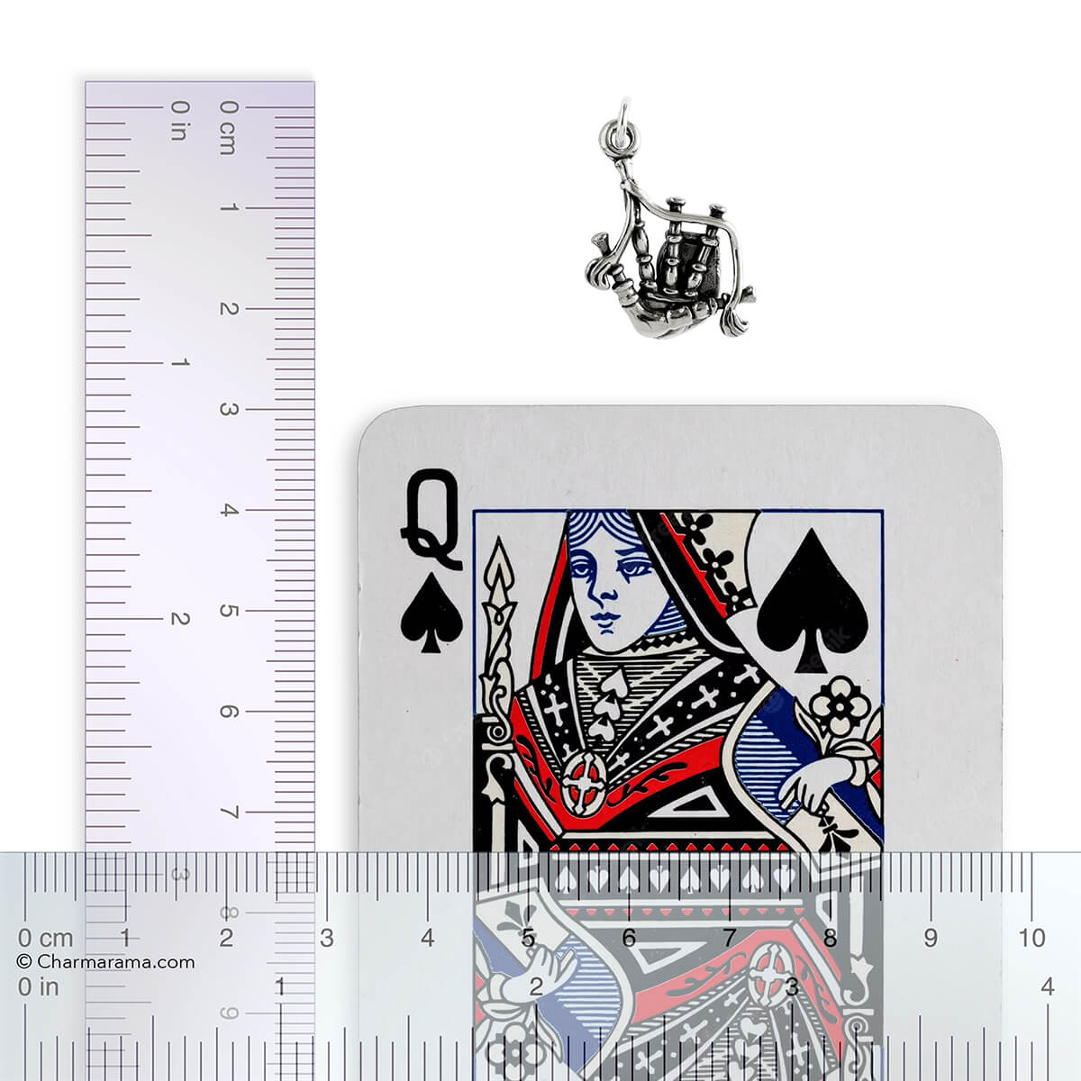 silver bagpipes charm on white background with ruler and playing card for scale