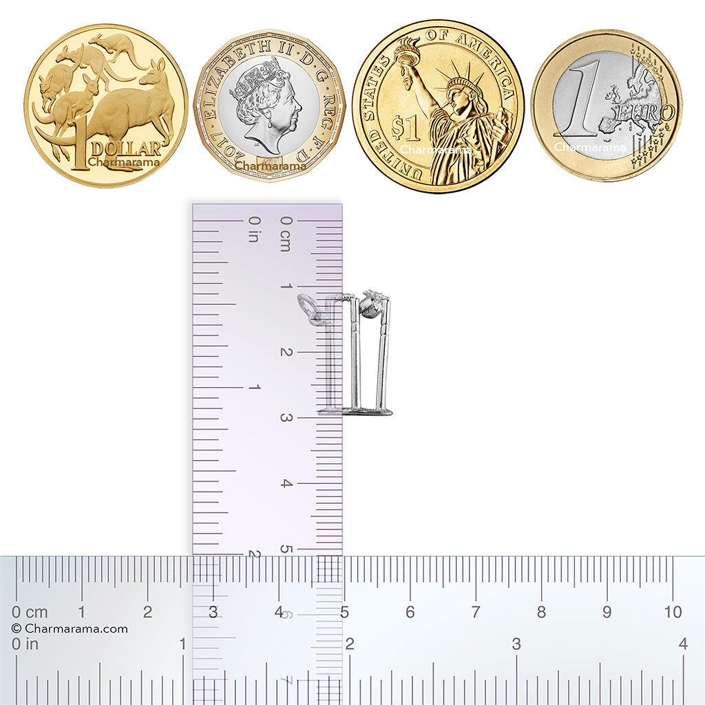 Sterling silver cricket stumps charm with coins and ruler for scale on a white background