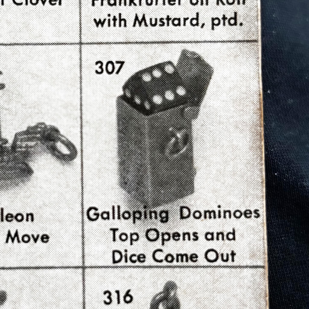 Vintage charm catalogue page with a dice box with dice on top, labelled 'Galloping Dominoes Top Opens and Dice Come Out'.