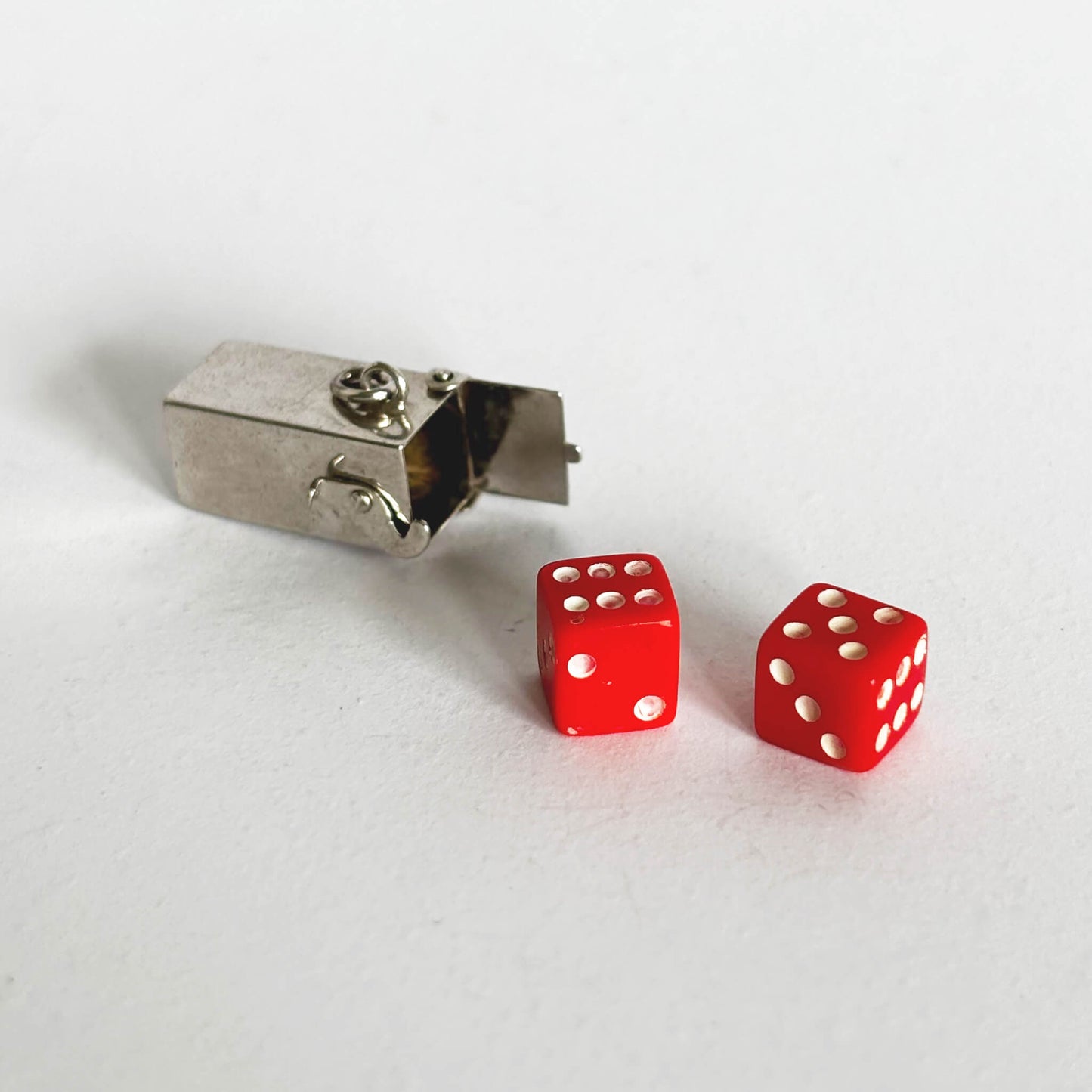 Two red dice with sterling silver box pendant on a white background