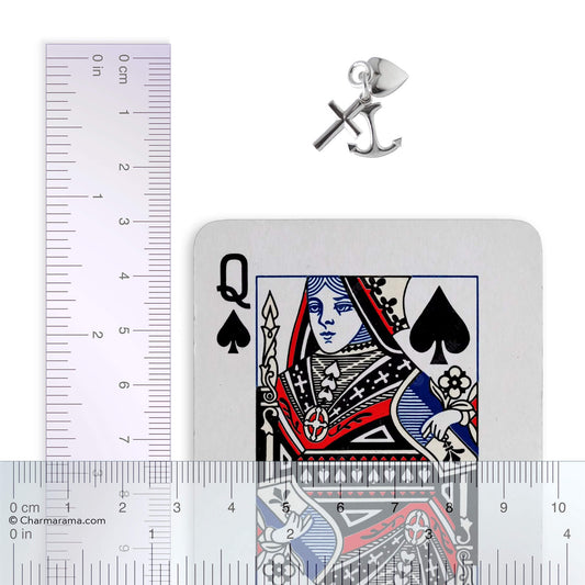 Sterling silver faith hope charity charm with playing card and ruler for scale on a white background