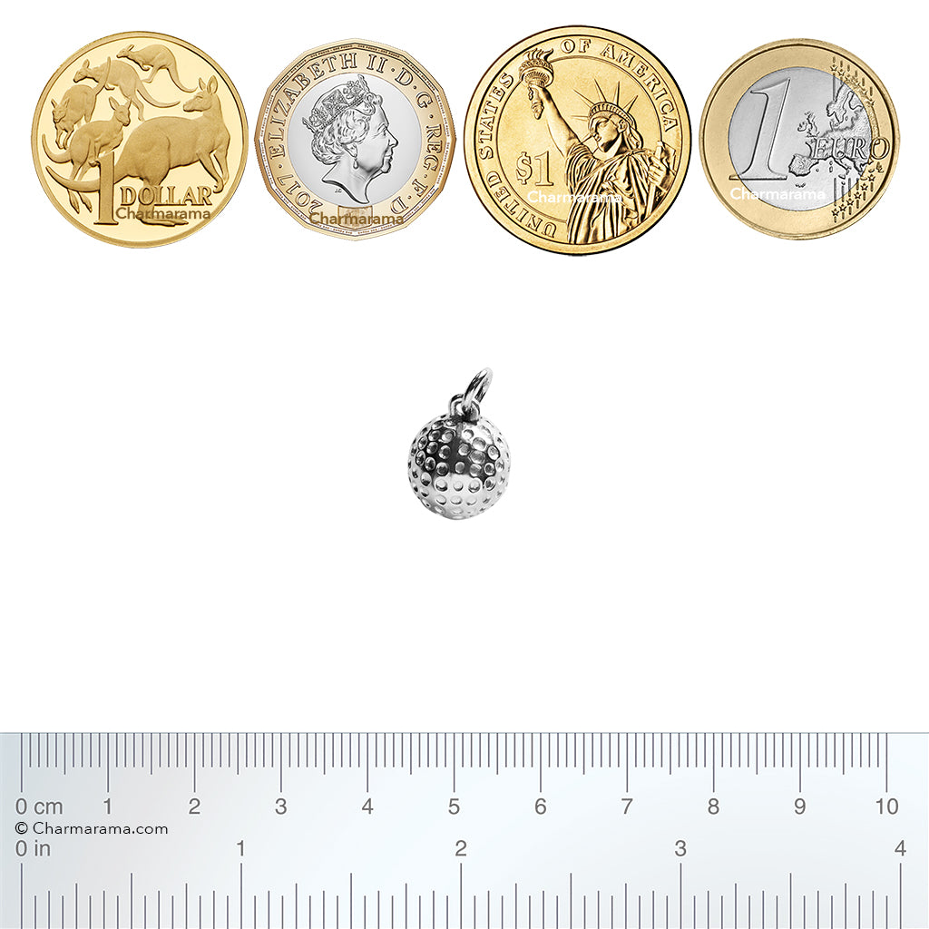 Sterling silver golf ball charm with coins and a ruler for scale on a white background.