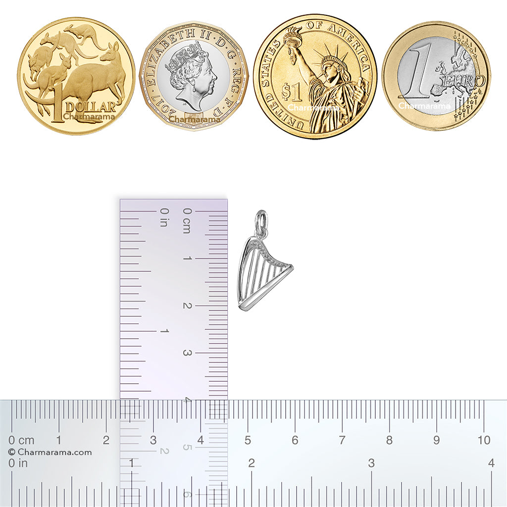 Silver harp pendant with a ruler for scale, alongside four international coins.