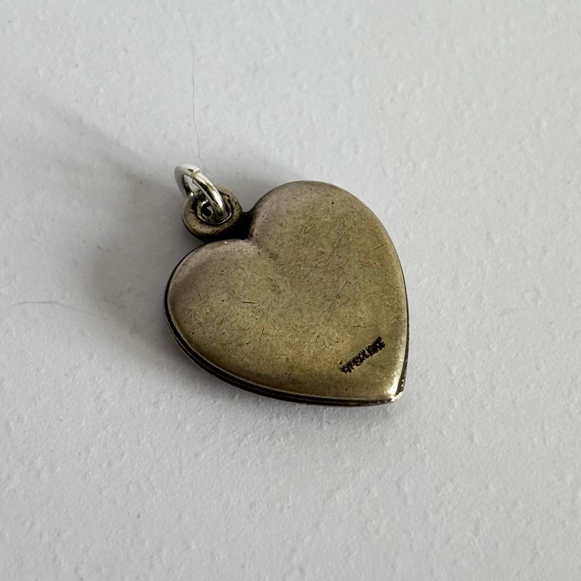 Heart-shaped silver pendant on a light gray background