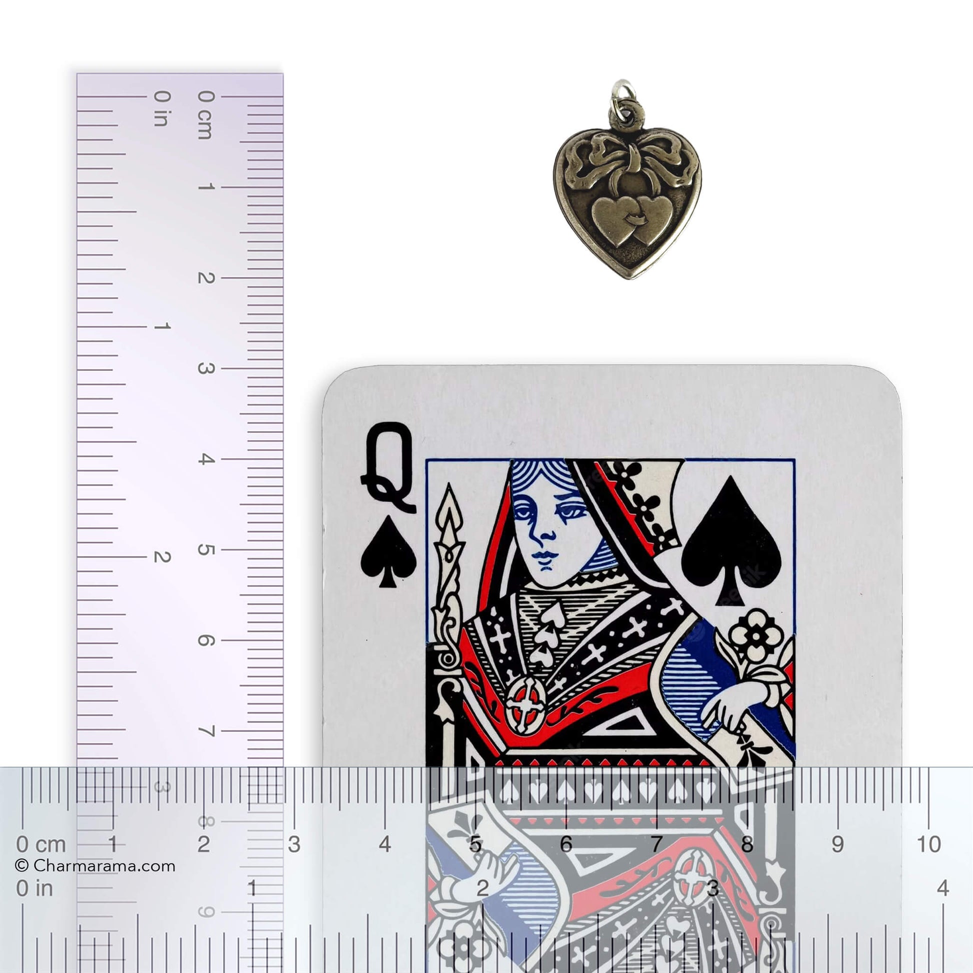 Heart-shaped pendant next to a playing card and a ruler for scale