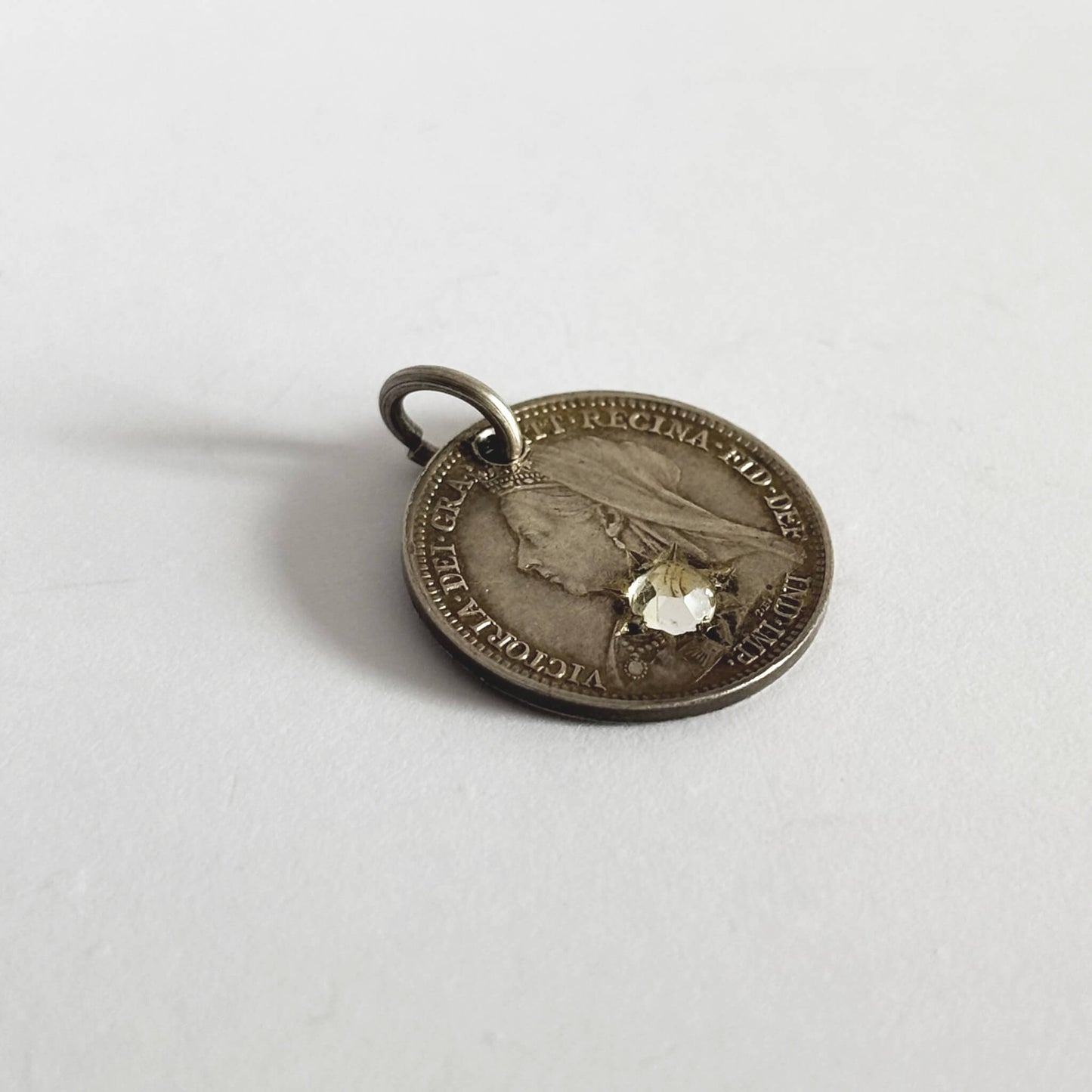 Victorian coin with a yellow gemstone on a white background