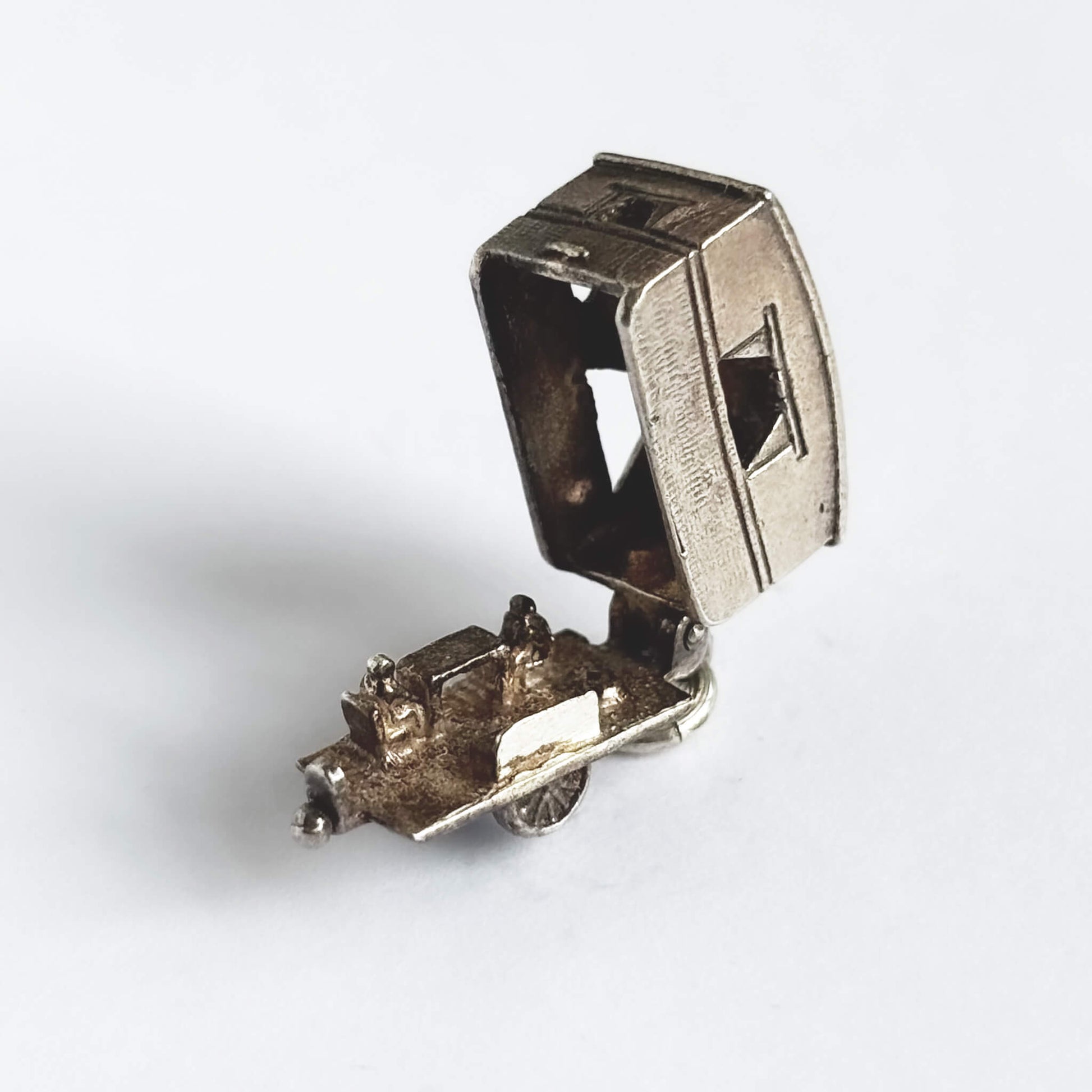 Vintage silver opening caravan charm on a white background.
