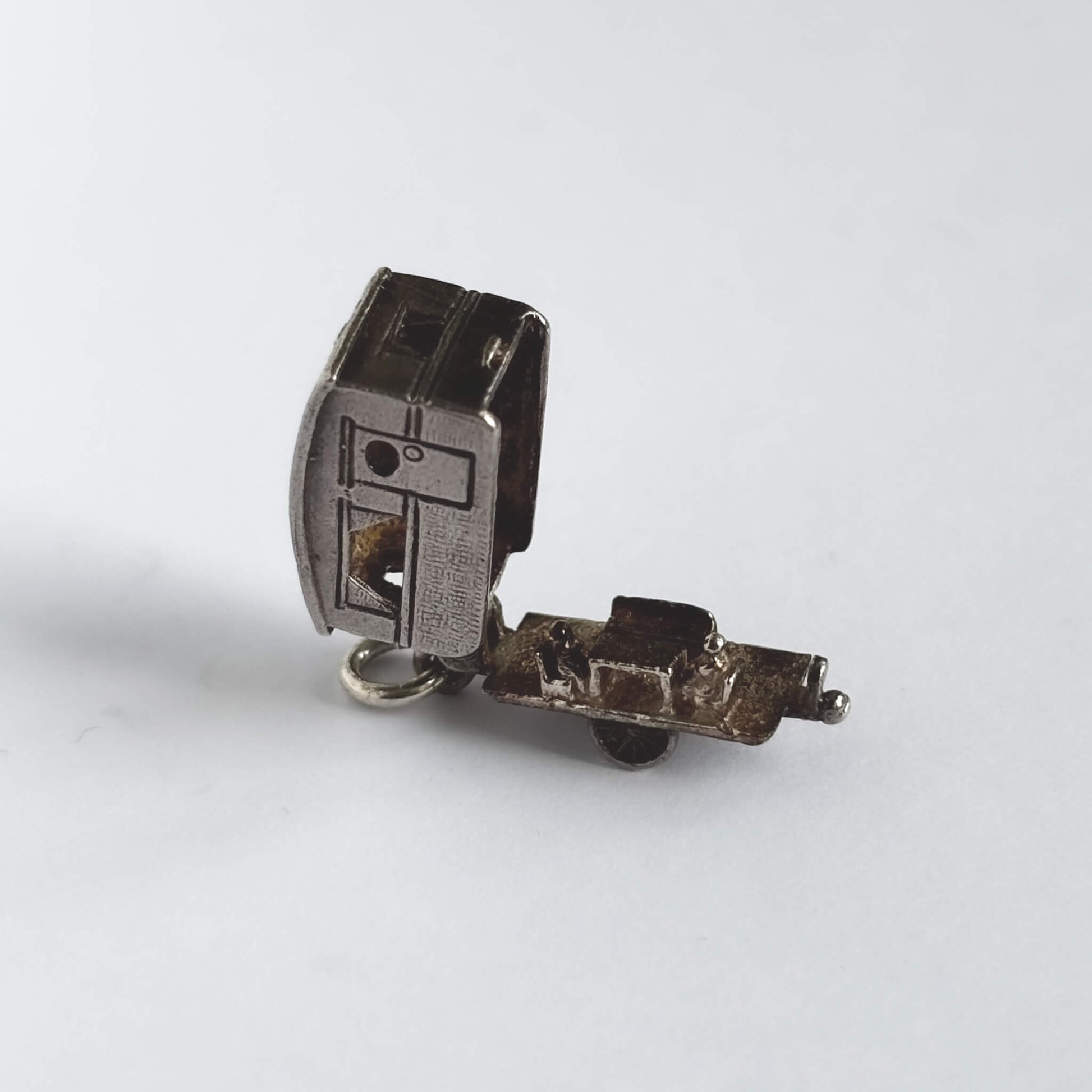 Vintage silver opening caravan charm on a white background.