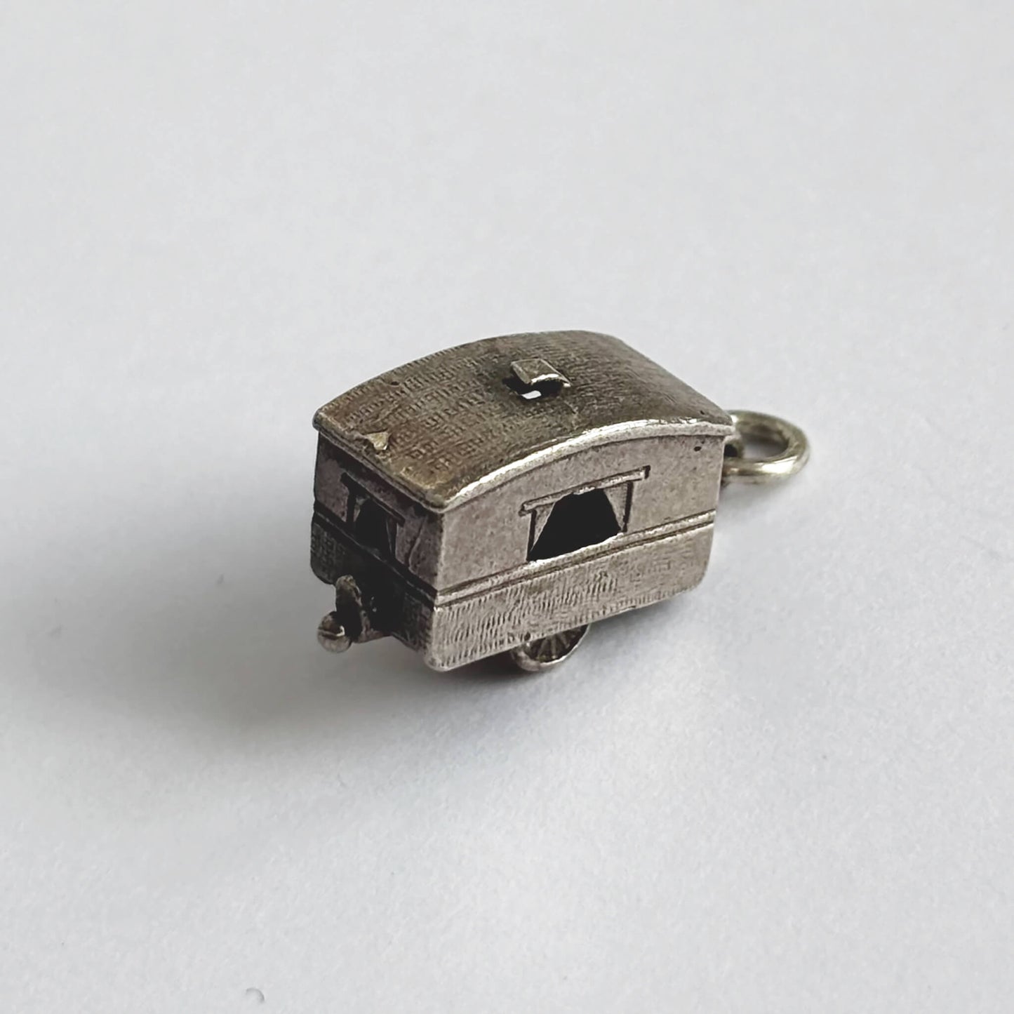 Vintage silver opening caravan charm on a white background.