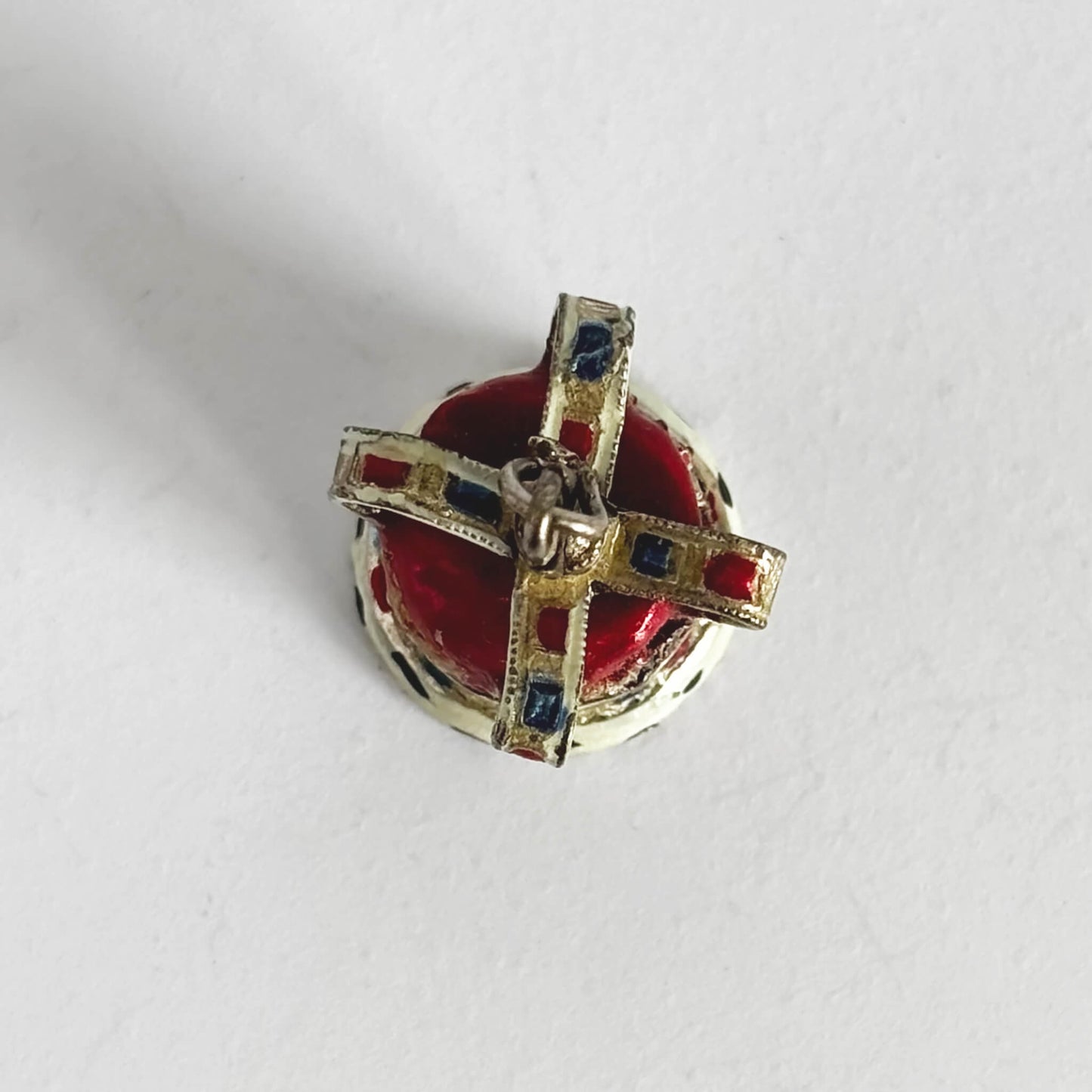 Silver and enamel crown pendant seen from above on a white background