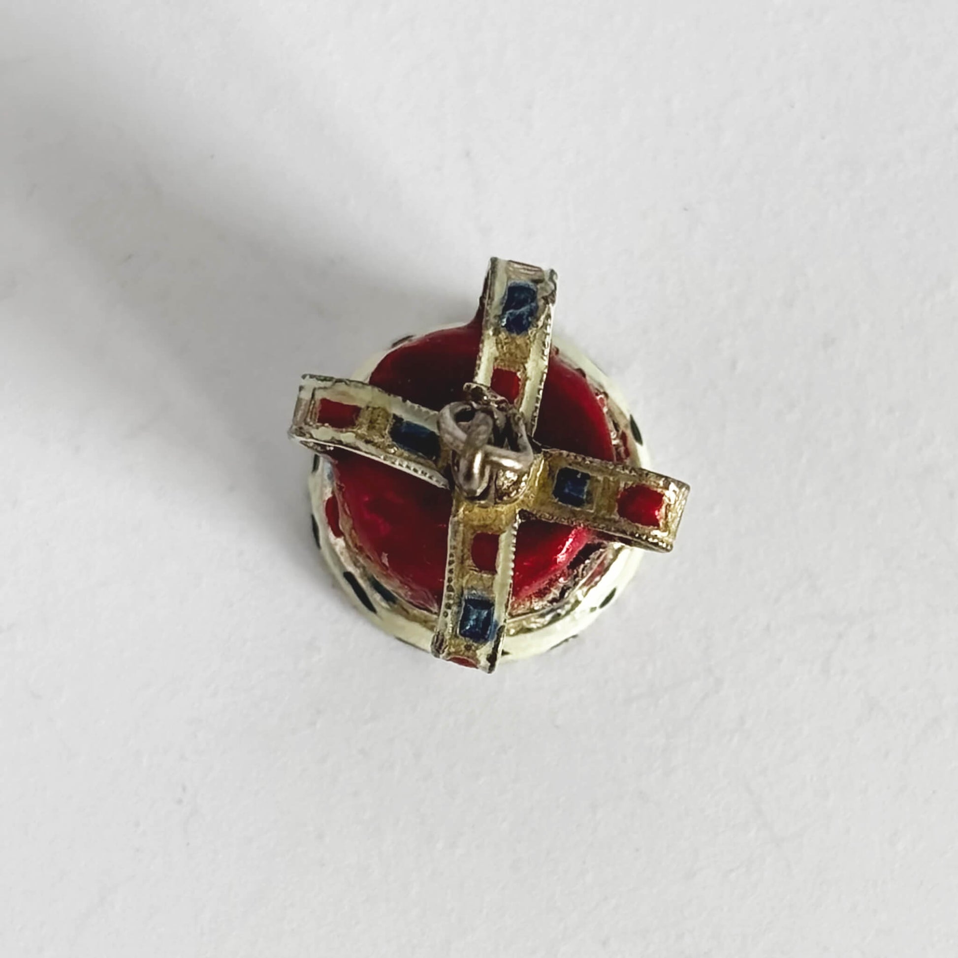 Silver and enamel crown pendant seen from above on a white background