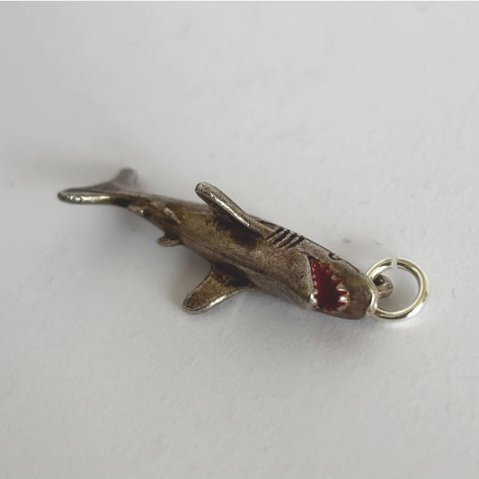 Silver shark charm on a white background