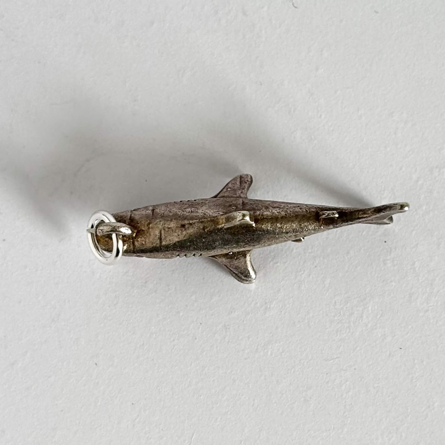 Silver shark pendant on a light gray background