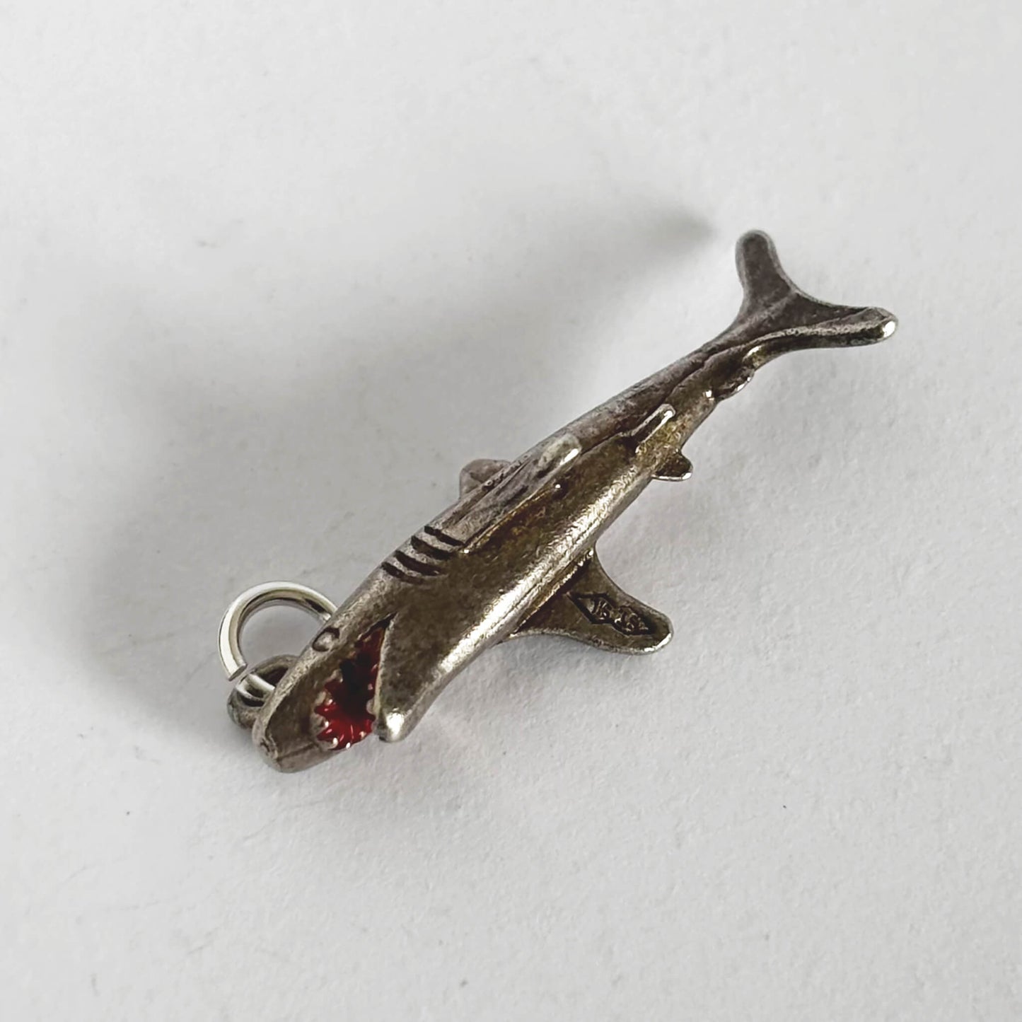 Silver shark charm on a white background