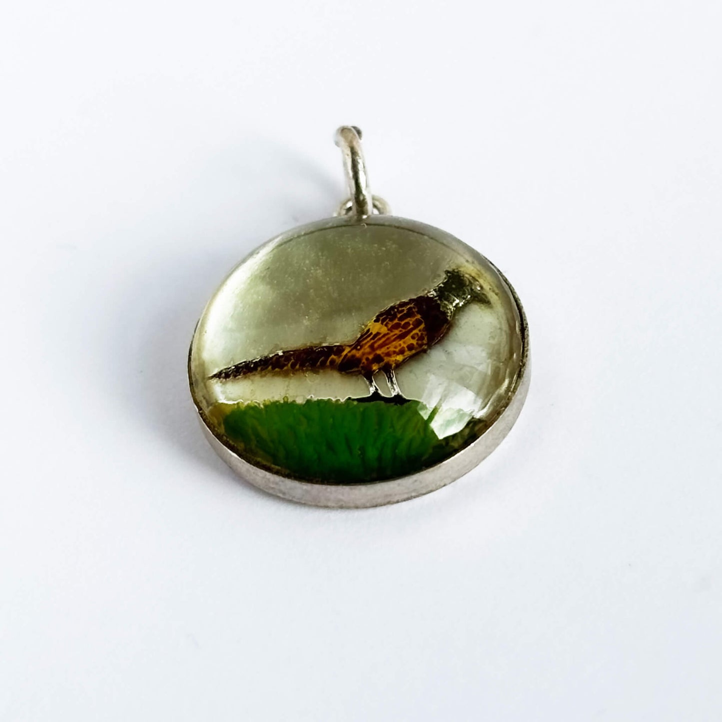 A vintage sterling silver reverse crystal pheasant charm on a white background.