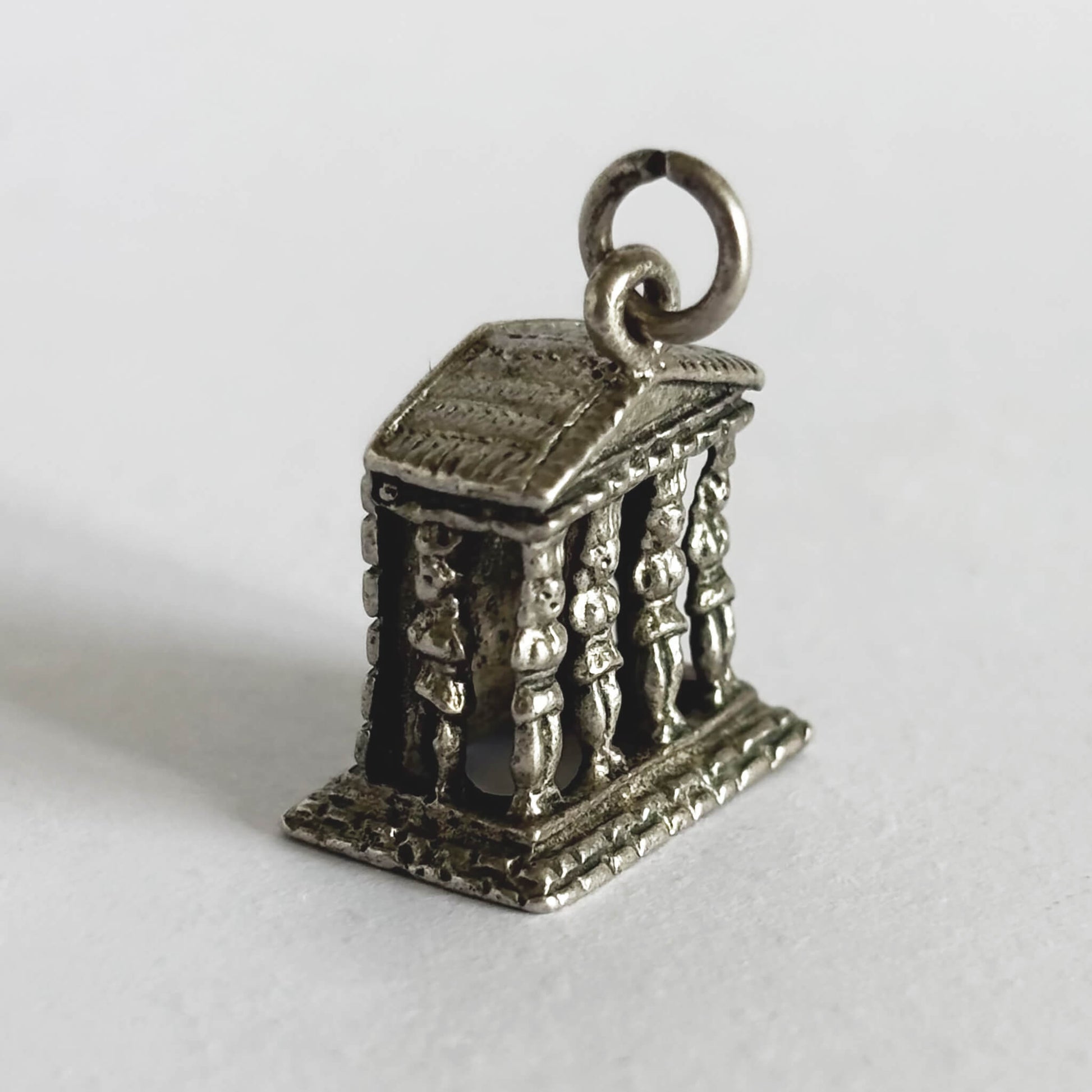 Silver Ancient Greek monument charm on a white background