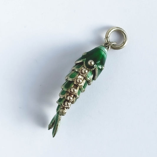 Vintage silver green enamel articulated fish charm on a white background.