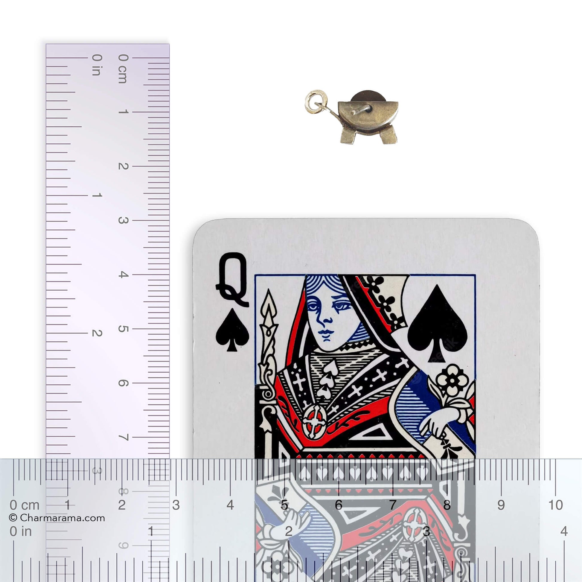 Vintage silver grindstone charm on a white background with playing card and ruler for scale.