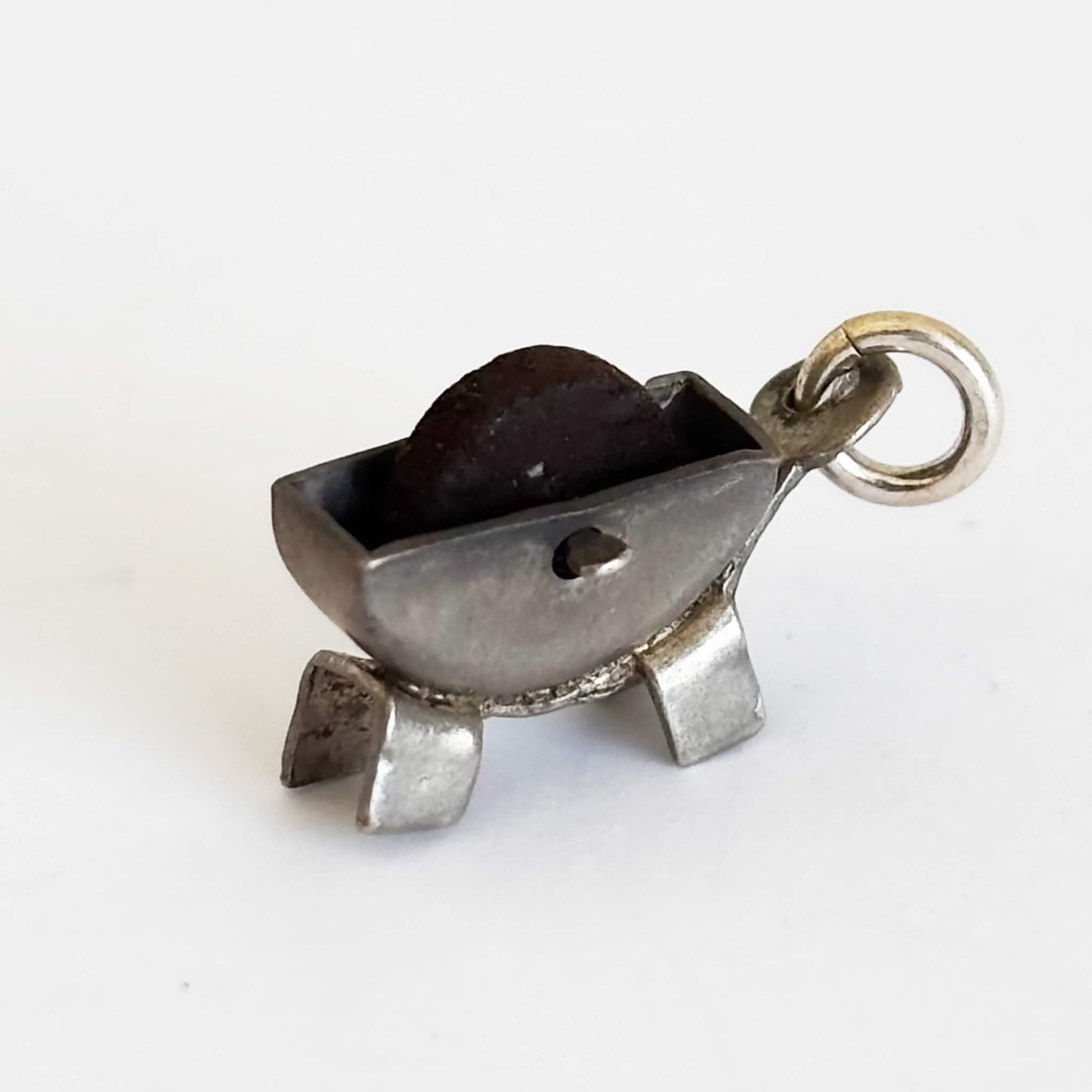 Vintage silver grindstone charm on a white background