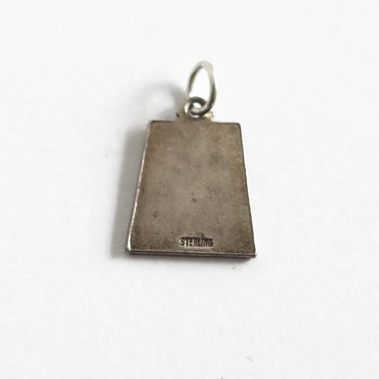 Back of silver trapezoid shape pendant with Libra zodiac sign and 'September' text with four dark blue enamel corner squares, on a white background