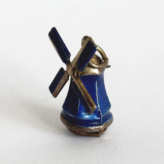 Vintage silver and blue enamel windmill charm on a white background