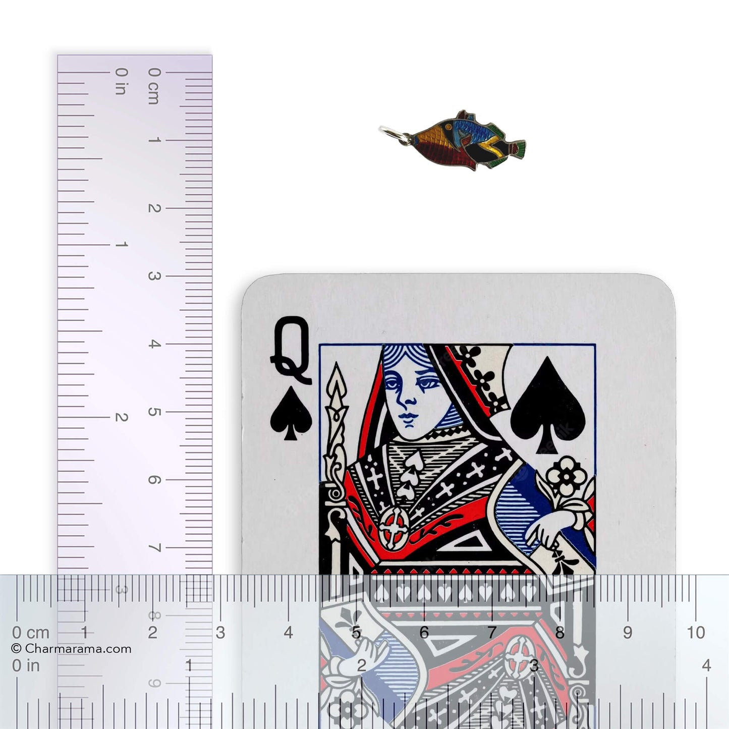 Vintage silver and colourful enamel tropical fish charm with playing card and ruler for scale on a white background