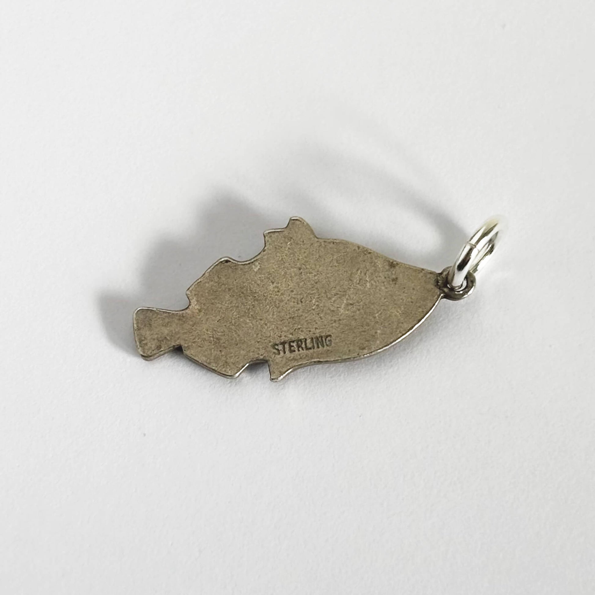 Back of a vintage silver tropical fish charm on a white background