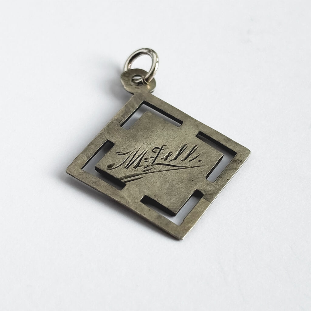 An antique silver and enamel Austrian lucky star charm on a white background.