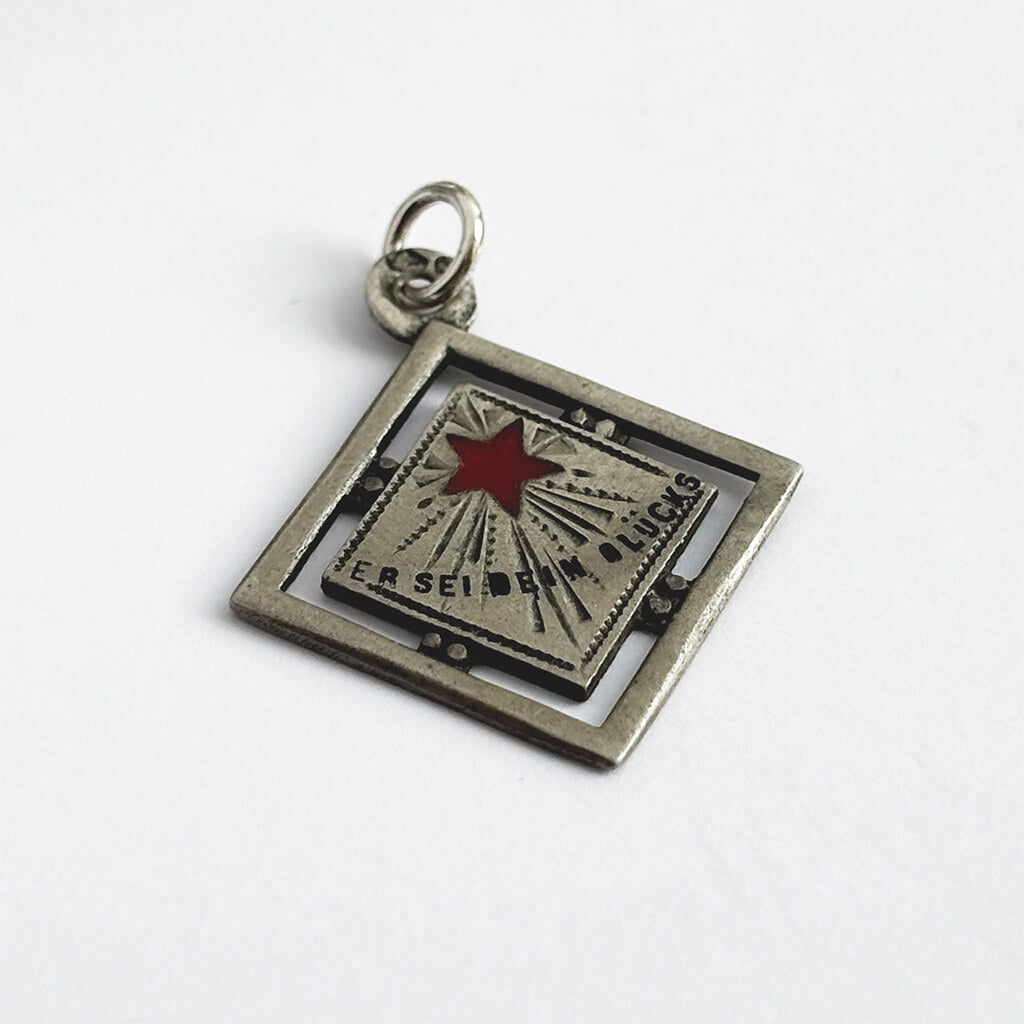 An antique silver and enamel Austrian lucky star charm on a white background.