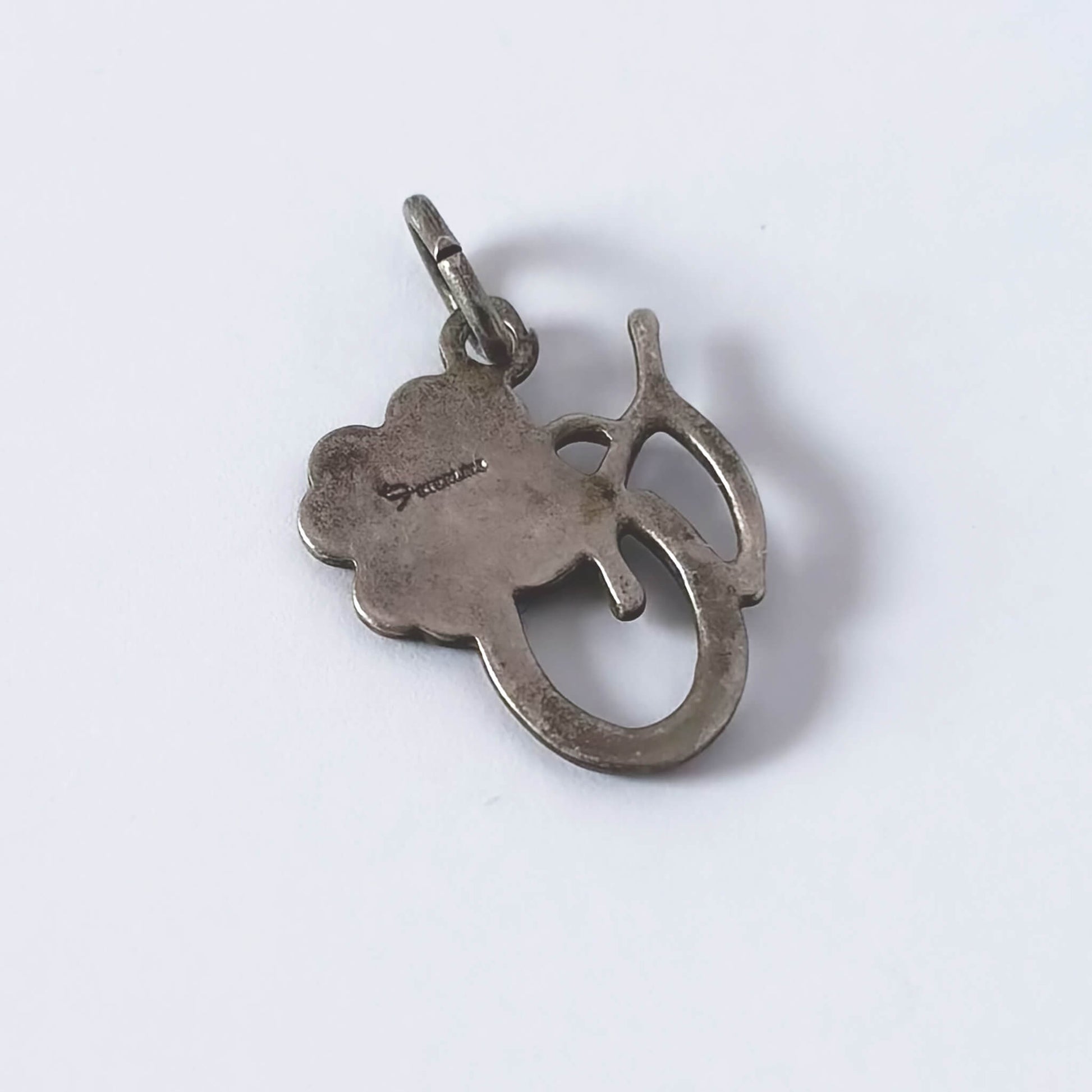 Silver pendant with a clover leaf design on a white background