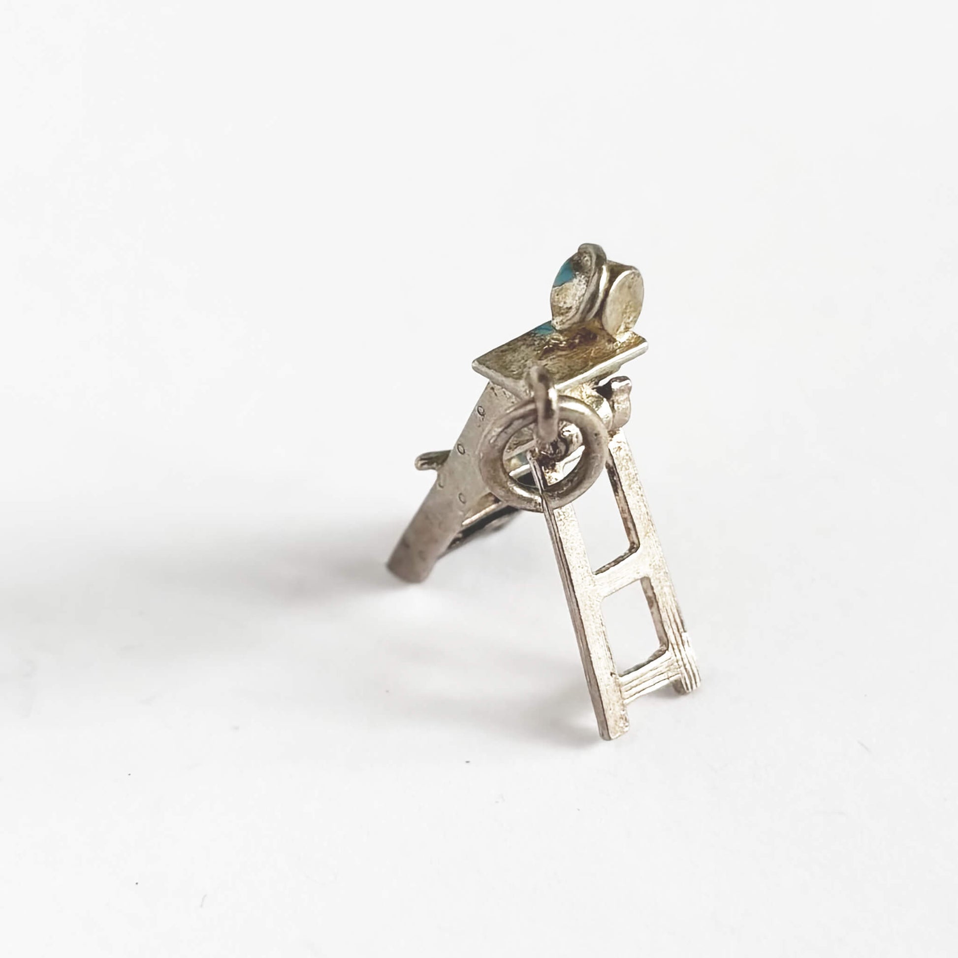 Silver charm with blue enamel on a white background