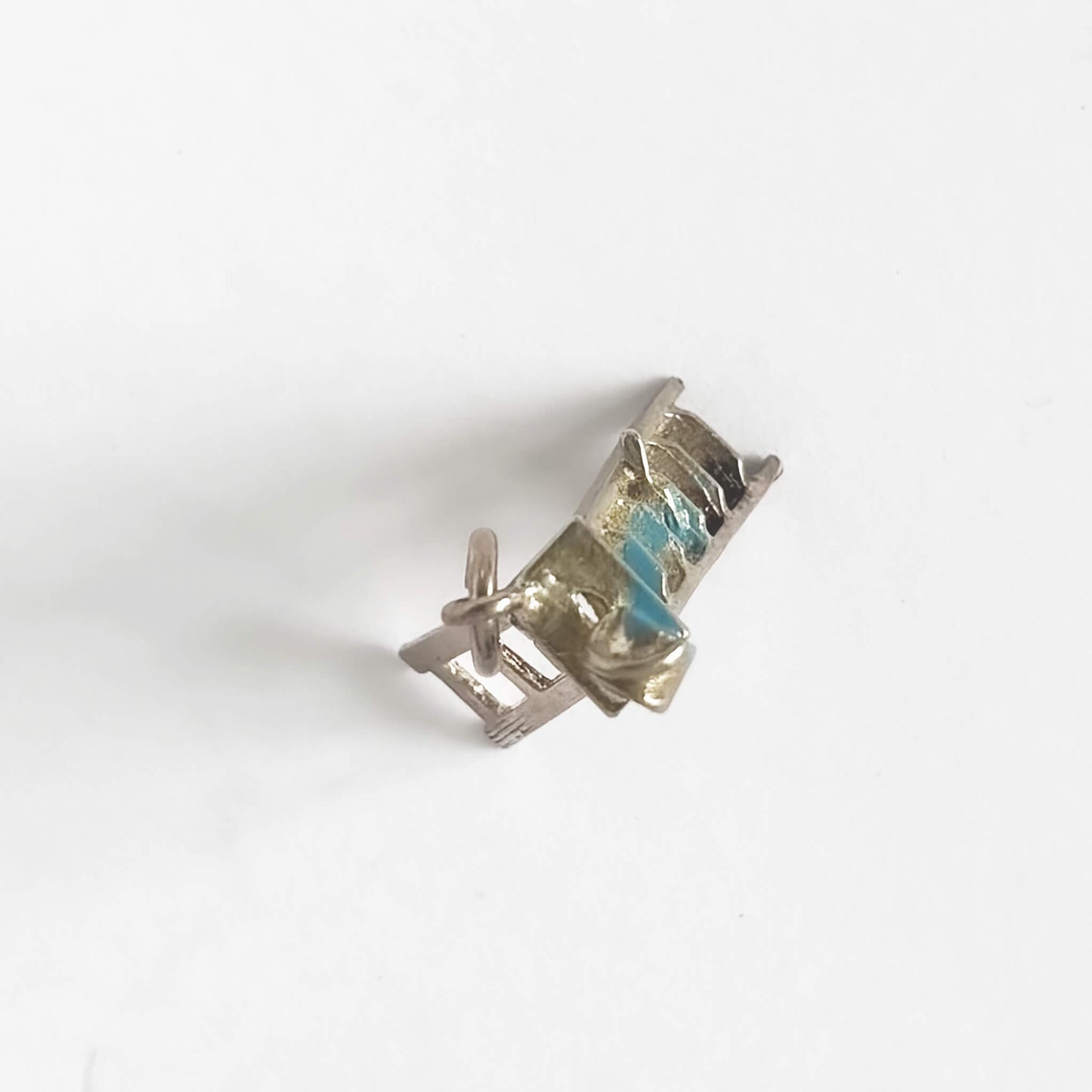 Silver ladder charm with a blue paint can on a white background