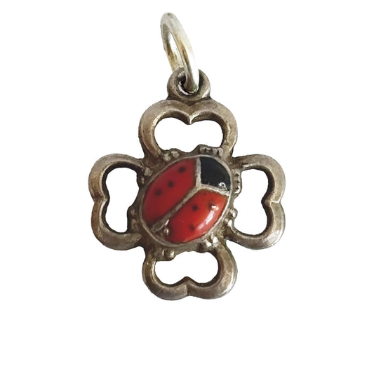 Silver pendant with a red ladybug design on a white background