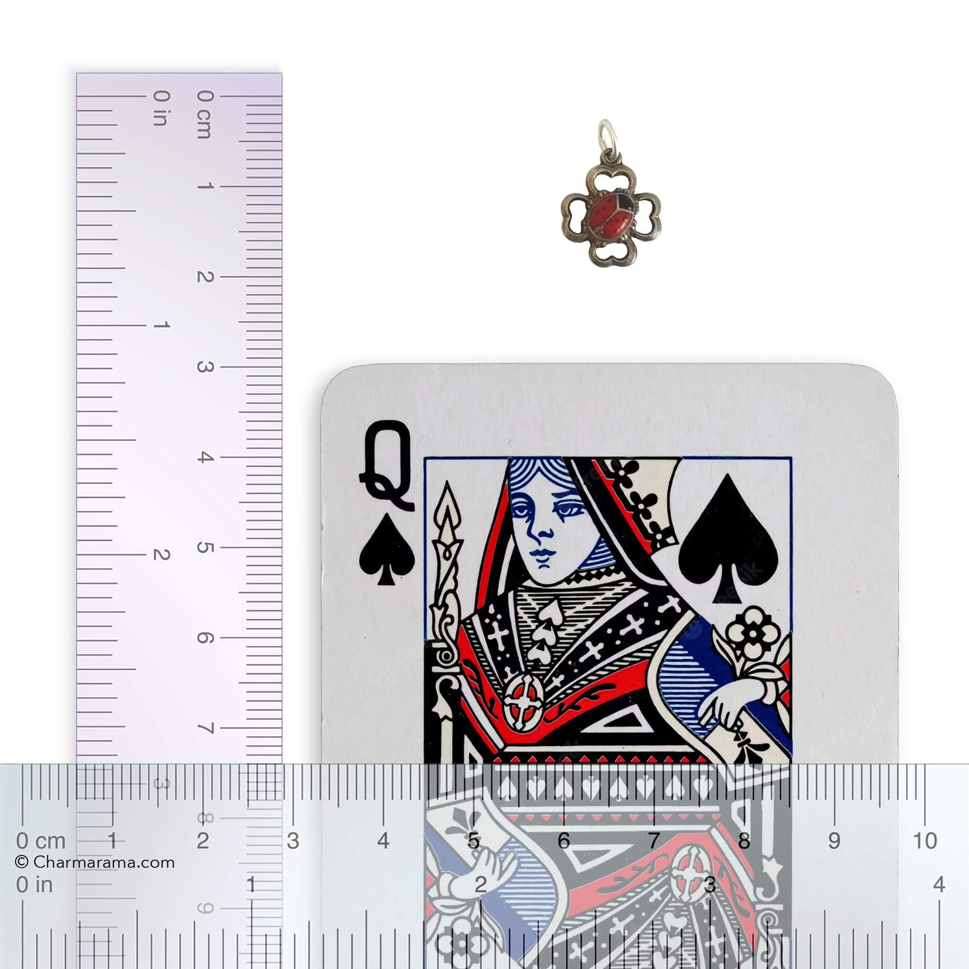 Pendant next to a playing card with a ruler for scale