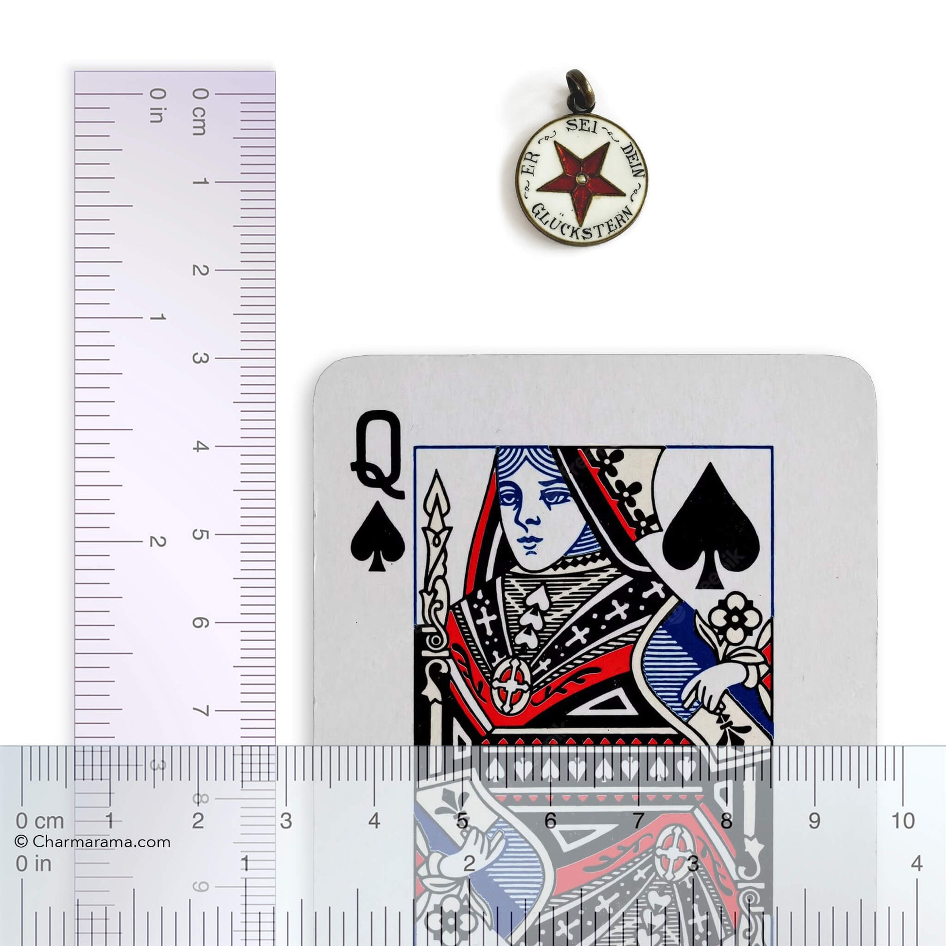 Playing card with Queen of Spades design, pendant, and ruler for scale on a white background