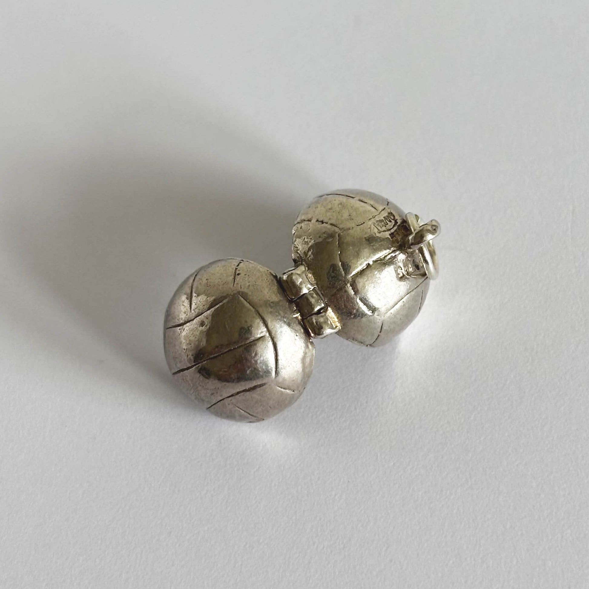 Vintage silver open Nuvo football charm shown from back on a white background